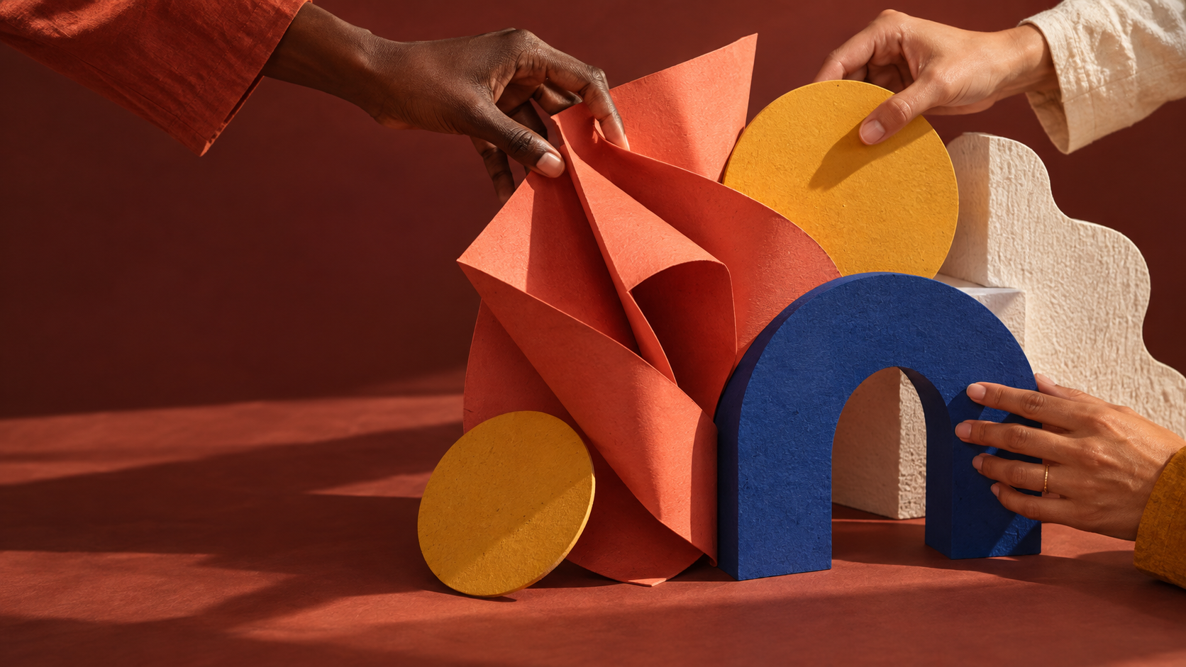 Manos construyendo juntas una composición de papel y formas de colores